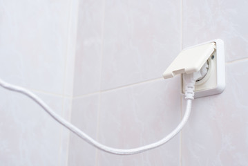 Еhe power plug is plugged in electrical socket in bathroom