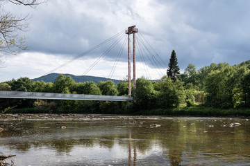 A suspension footbridge with an observation tower stands over the river San at the historic border between Poland and the USSR.