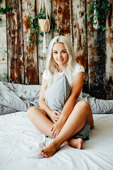 Cute woman holding a pillow while sitting on bed