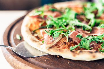 pizza with ham, mozzarella, tomato sauce from the oven on wooden plate in restaurant of Catania, Sicily, Italy.