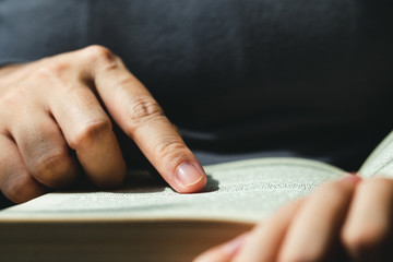 close-up of finger pointing text in Bible.close up of man reading through the Bible.