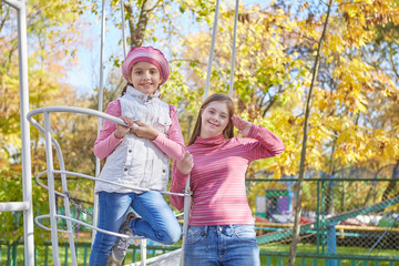 Girl with Down syndrome and little girl in autumn park.