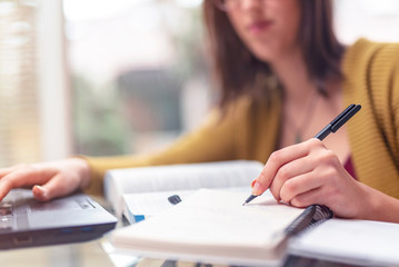 A young girl studying at home, writing down notes