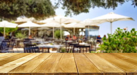 Wooden table background with blurred outside restaurant view. Empty  space for your decoration and...
