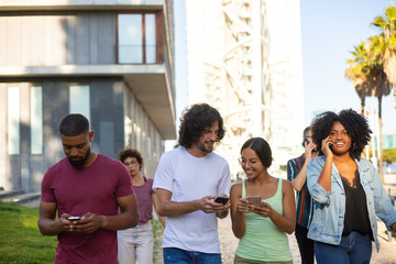 People with smartphones walking down street. Multiethnic men and women walking outside, talking on mobile phones and texting messages. Communication concept