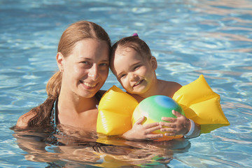 mother and daughter in armrests for swimming on vacation in the pool. The concept of Spa, swimming lessons, vacations, water treatment