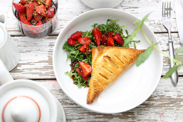 Baked ravioli pie with ricotta served with arugula and strawberry salad in balsamic vinegar with green pepper.