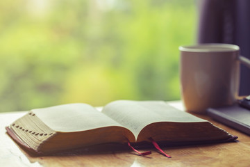  Open bible with a cup of coffee for morning devotion on wooden table with window light