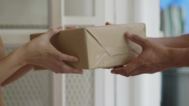 Slow Motion: Close up hands Asian woman receive a cardboard box from a man's delivery holding at home.