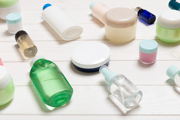 Close-up view of cosmetic bottles, jars, containers and sprays on white wooden background. Beauty concept with copy space