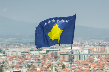 waving flag of Kosovo in front of blurred city