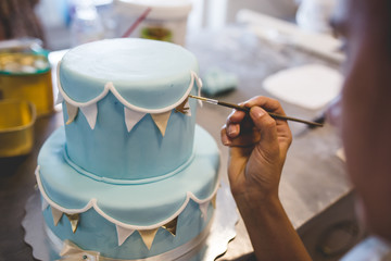 A woman decorates and makes cakes in a pastry shop