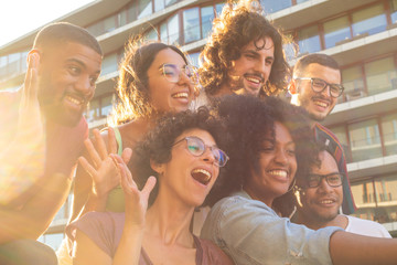 Joyful multiethnic friends taking funny group selfie outside. Mix raced men and women posing, grimacing and smiling at phone camera. Having fun together concept