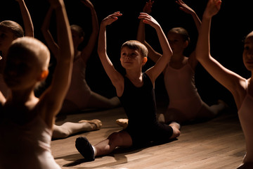 Children doing splits while warming up on the stage
