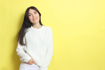 Fototapeta premium Beautiful girl in a warm cozy sweater on a colored background.