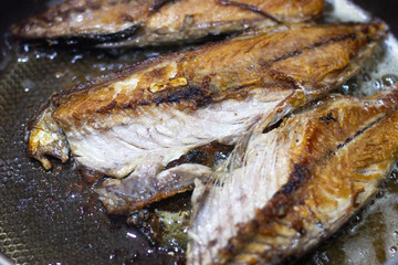 mackerel fish fried in pan oil thai style food. Mackerel fried in a black pan. Fish fried in a black pan