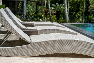 Relaxing rattan deckchairs beside swimming pool. Summer vacation
