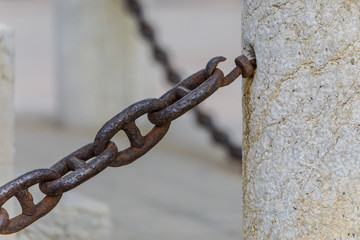 Rostige Kette als Absperrung in einer Wand verankert, Detail