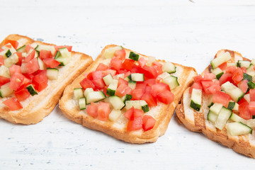 Italian bruschettas with sliced tomato cucumbeand vegetables. Vegetarian bread toast with fresh cucumber and tomato.
