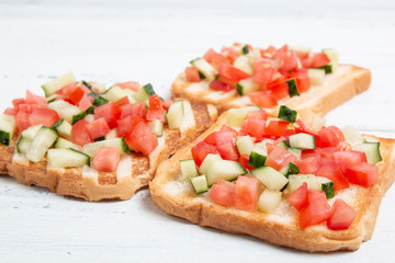 Italian bruschettas with sliced tomato cucumbeand vegetables. Vegetarian bread toast with fresh cucumber and tomato.