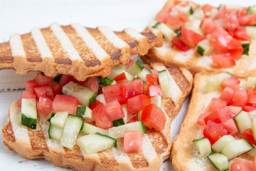 Italian bruschettas with sliced tomato cucumbeand vegetables. Vegetarian bread toast with fresh cucumber and tomato.