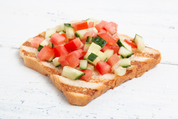 Italian bruschettas with sliced tomato cucumbeand vegetables. Vegetarian bread toast with fresh...