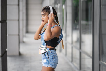 Young girl listening to podcast via headphones on the street