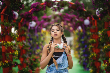 Fototapeta premium portrait of modern teenage girl with headphone. Blooming flowers at background