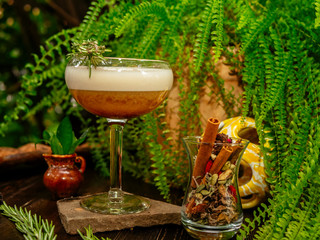 Brown cocktail in a glass goblet on a long leg. In the tropical garden. On a flat stone.