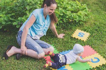 A young mother with a baby rest on a green lawn