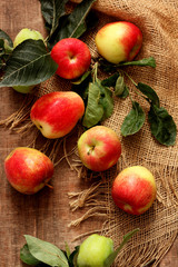 red apples with leaves on wooden background