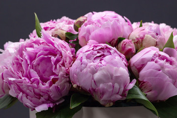Pink peonies in a hat box on a dark background.