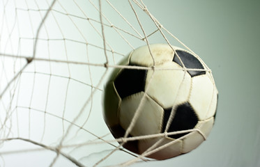 Scoring goal, Soccer ball in the net against gray background.