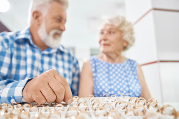 Senior man choosing gold ring for his wife in jewelry store