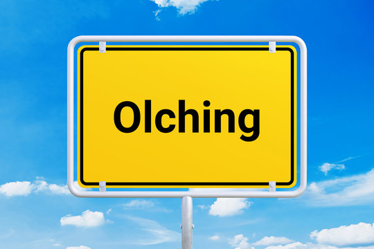 Stadt Olching. Gelbes Schild, Ortsschild, Ortseingangsschild. Himmel mit Wolken.