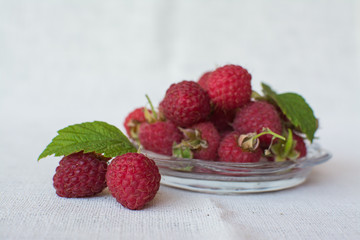 Fresh, sweet raspberries in a transparent glass cup.