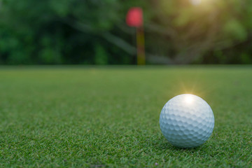 Golf ball on green in beautiful golf course at sunset background.