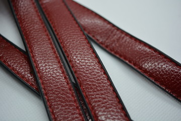 Cherry red belt, genuine cowhide leather strap with metal carbines on a white fabric photo...