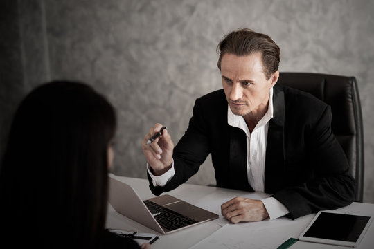 Young Business Man In Black Suit Are Angry And Furious Fierce On  Complain Subordinate At The Desk In The Office Work In Dark Tone. Business Stress And Job Problem Concept