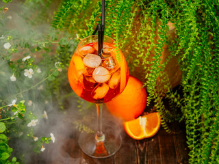 Orange aperol cocktail. On the summer terrace. Garden plants. Sunny day. Orange drink