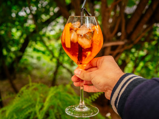 Orange aperol cocktail. On the summer terrace. Garden plants. Sunny day. Orange drink