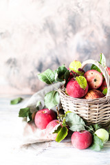Red apples in a wicker basket on a wooden table, blurred background.