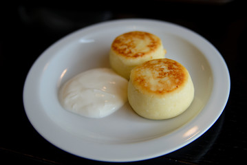 Two cheesecakes on a white plate with sour cream