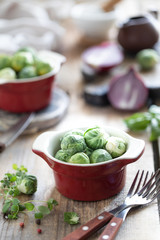 Young raw brussels sprouts in a metal cup on a wooden background