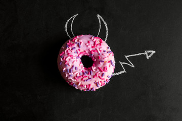 top view donut on chalk board with chalk-drawn horns and a tail