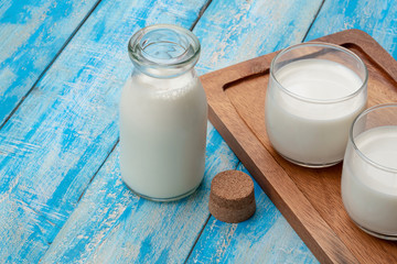 A bottle of milk and glass of milk on a blue wooden table, healthy dairy products concept