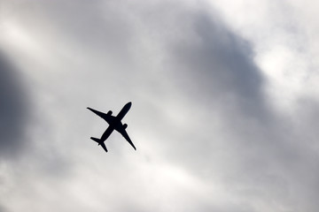 Airplane silhouette on storm sky background. Commercial plane taking off among dark clouds, turbulence concept