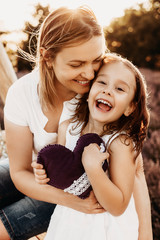 Close up portrait of a lovely mother and daughter embracing and laughing while looking at camera...