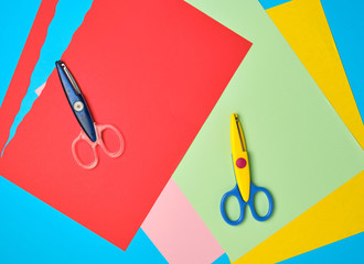 pair of plastic scissors and colored paper for cutting figures