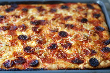 Homemade pizza with tomato sauce, parmesan cheese, pepperoni, chorizo and onion. Selective focus.